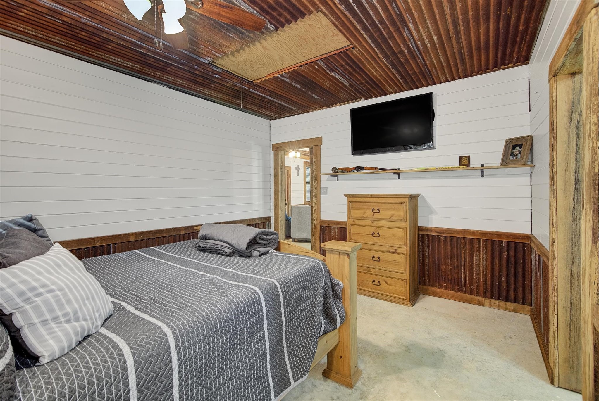 22546 Highway 321 Cleveland, TX 77327 - Photo 19 of 34 a bedroom with a bed and a flat tv screen on wall