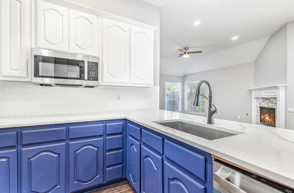 3674 Crowberry Way Fort Worth, TX 76040 - Photo 16 of 26 Kitchen with appliances with stainless steel finishes, ceiling fan, backsplash, white cabinets, and lofted ceiling