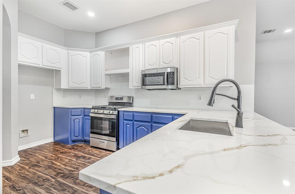 3674 Crowberry Way Fort Worth, TX 76040 - Photo 17 of 26 Kitchen with appliances with stainless steel finishes, blue cabinets, white cabinetry, open shelves, and backsplash