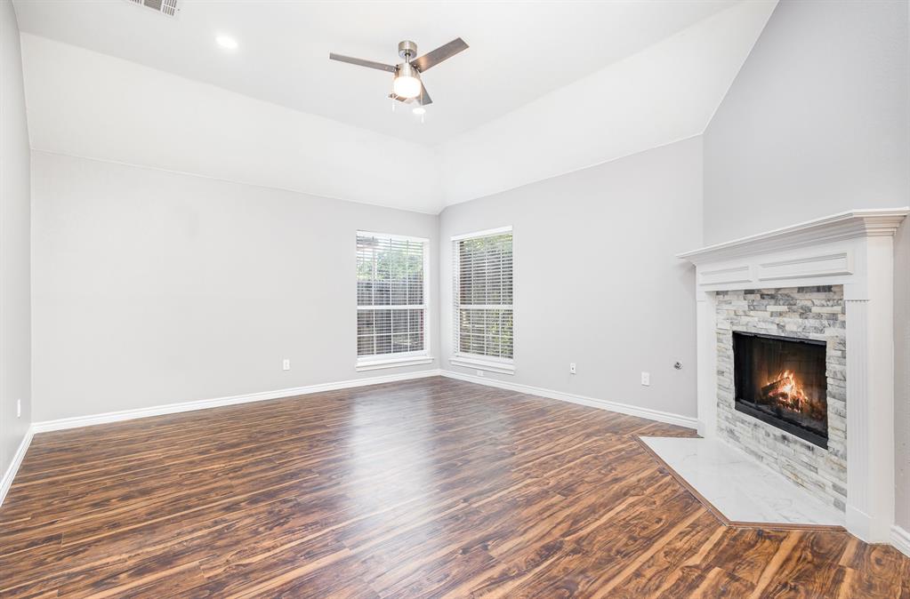 3674 Crowberry Way Fort Worth, TX 76040 - Photo 9 of 26 Unfurnished living room with wood finished floors, a fireplace, ceiling fan, and lofted ceiling