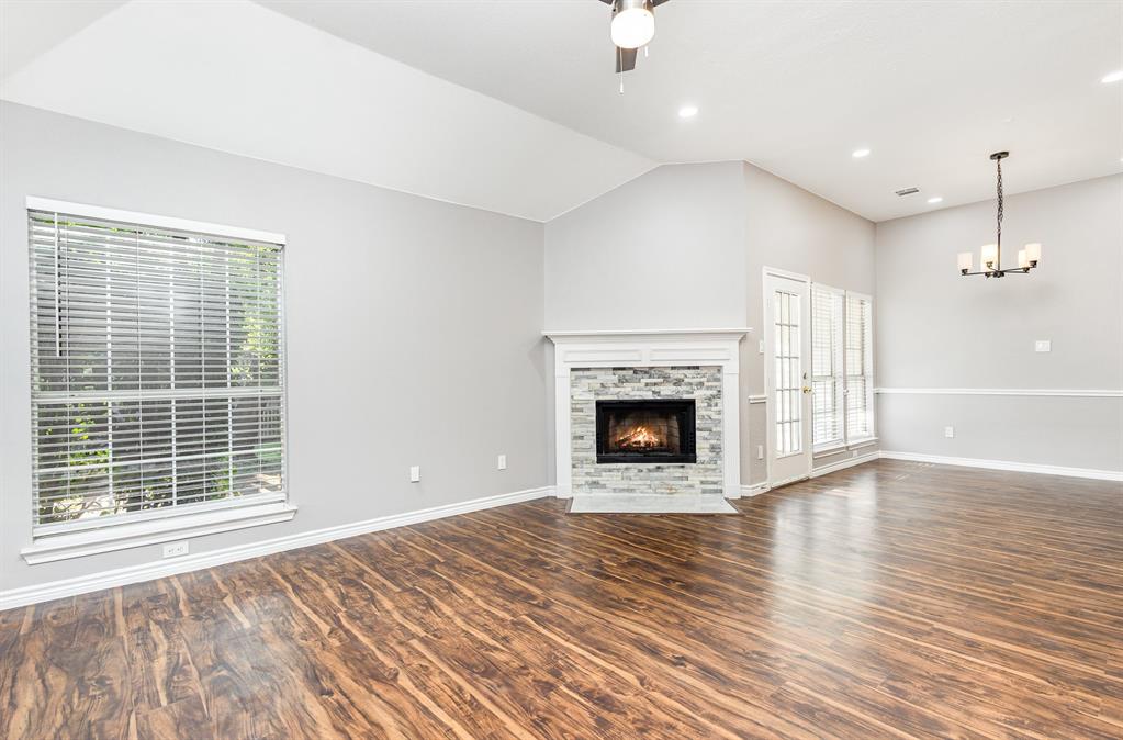 3674 Crowberry Way Fort Worth, TX 76040 - Photo 10 of 26 Unfurnished living room featuring a ceiling fan, wood finished floors, a fireplace, a chandelier, and vaulted ceiling