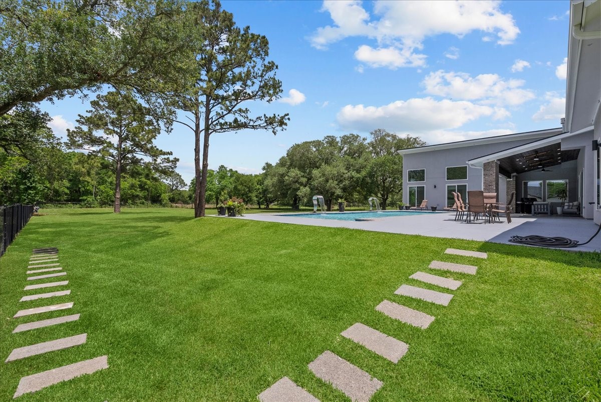 7627 Scott Avenue Manvel, TX 77578 - Photo 45 of 50 Modern stepping stones lead across a sprawling, lush lawn toward the resort-style pool and terrace.