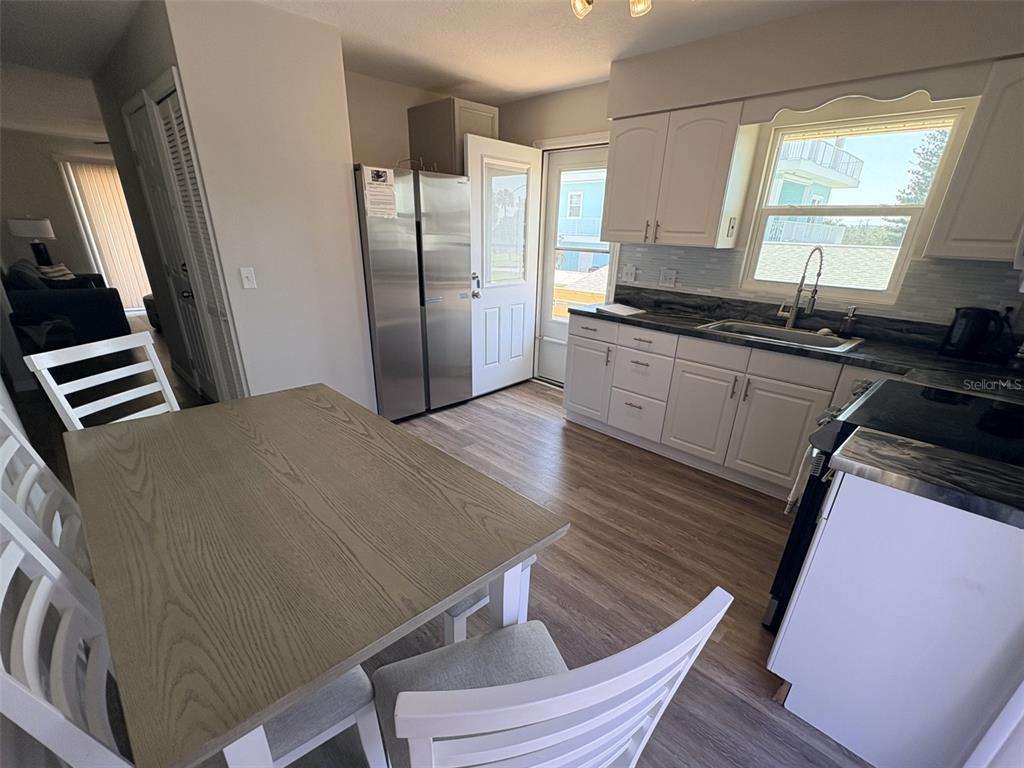 6693 Engram Road New Smyrna Beach, FL 32169 - Photo 2 of 18 a kitchen with wooden floors and refrigerator