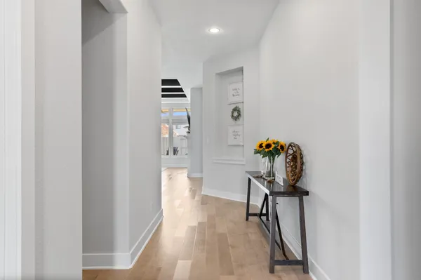 a view of a hallway with wooden floor and a bathroom