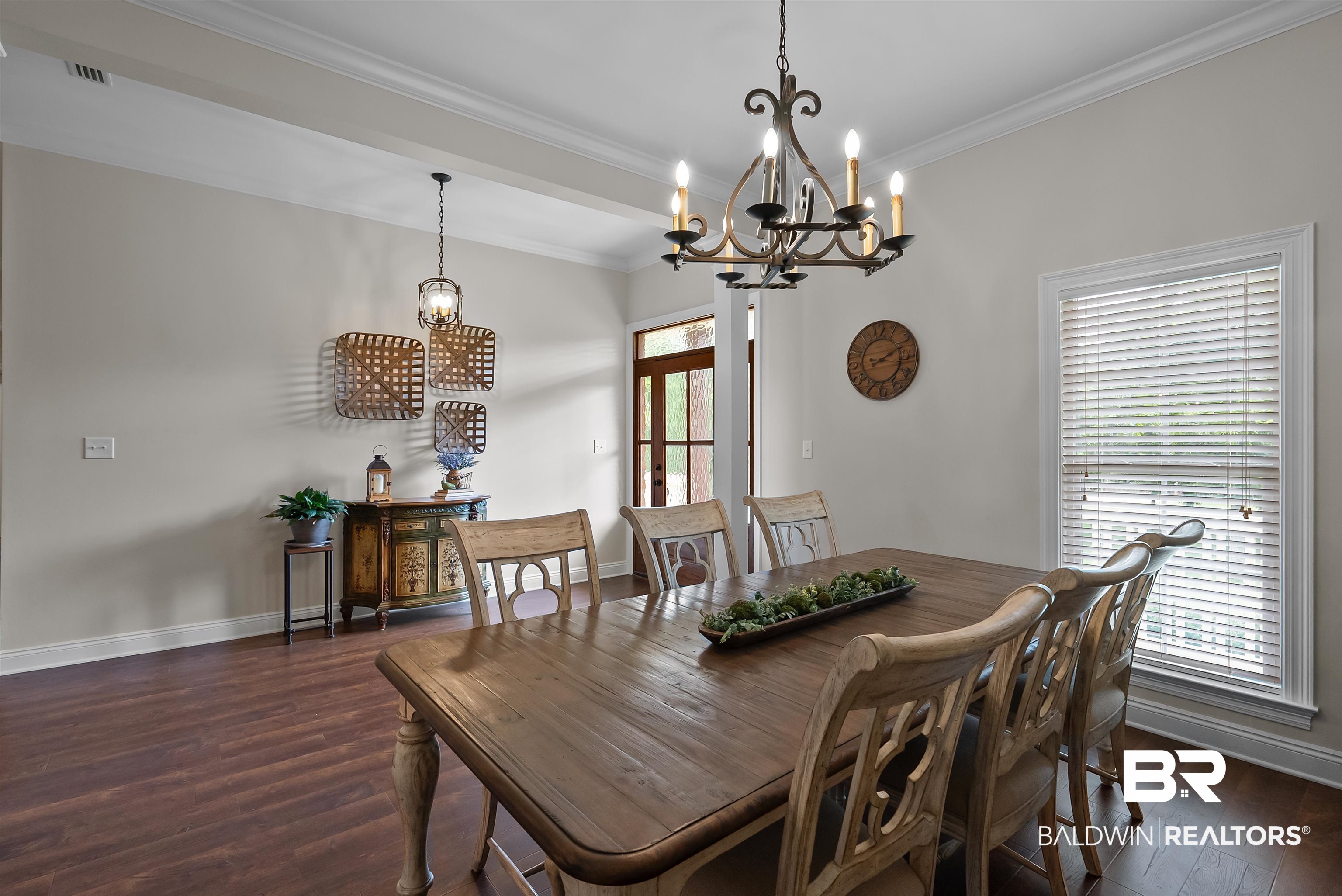 12070 Comalander Road Fairhope, AL 36532 - Photo 4 of 50 Dining room with wood-finish flooring, overhead chandelier, white trim, and a prominent window with blinds