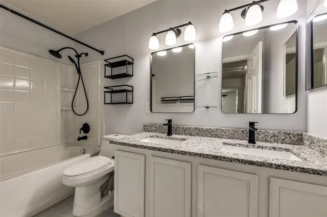 a bathroom with a granite countertop sink a toilet a mirror and shower
