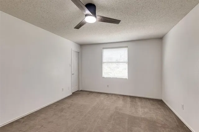 an empty room with a window and a ceiling fan