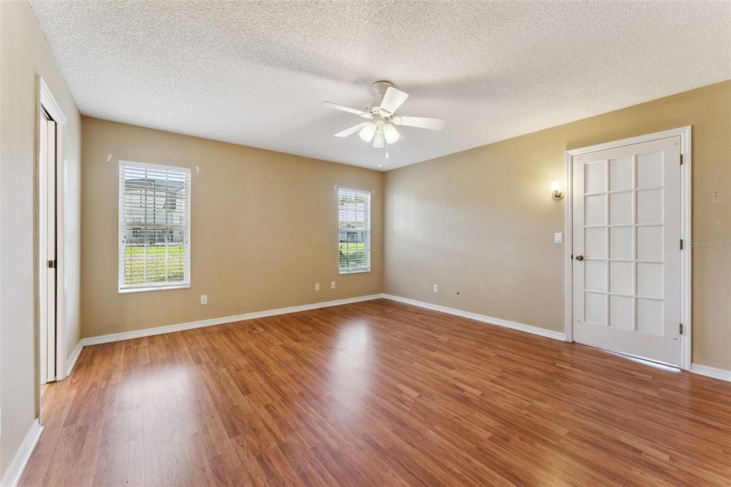 27217 Racquet Circle Leesburg, FL 34748 - Photo 19 of 90 an empty room with wooden floor chandelier fan and windows