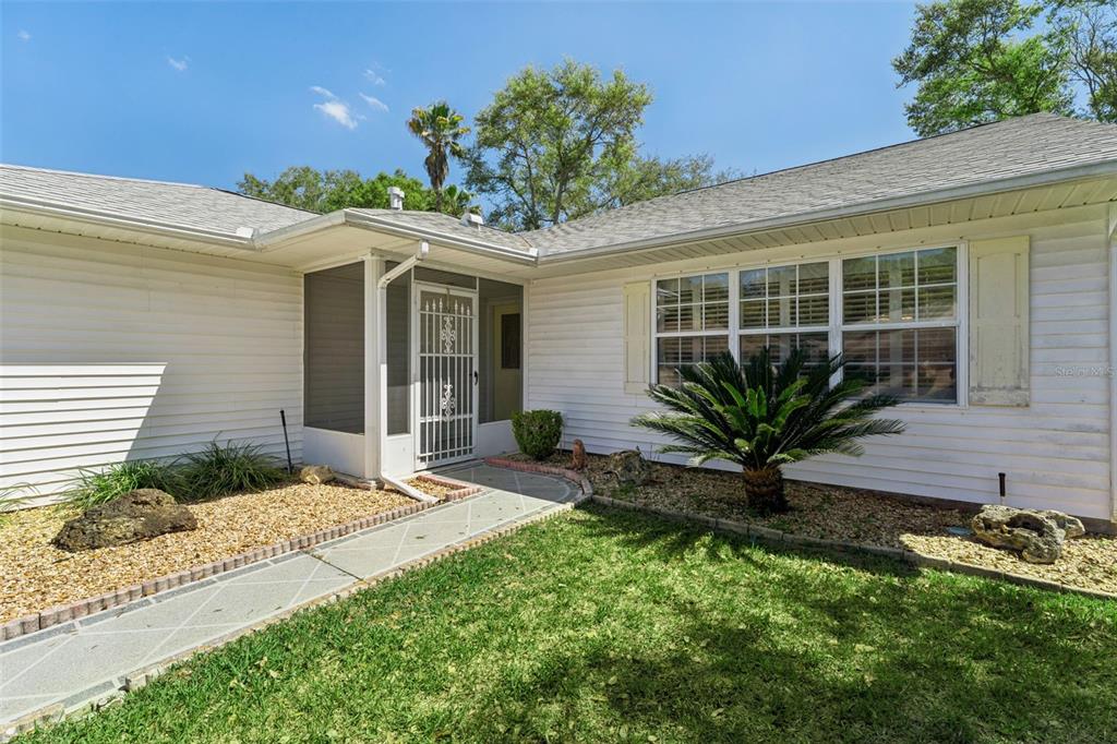 27217 Racquet Circle Leesburg, FL 34748 - Photo 3 of 90 a front view of a house with a yard and potted plants