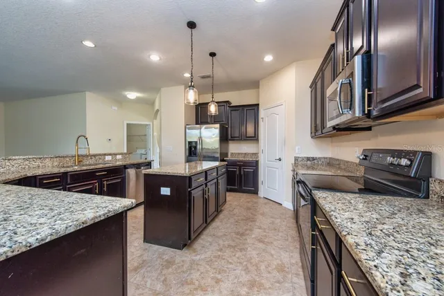 a kitchen with stainless steel appliances granite countertop a stove a sink a oven and a refrigerator