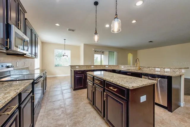 a kitchen with stainless steel appliances granite countertop a sink refrigerator and cabinets
