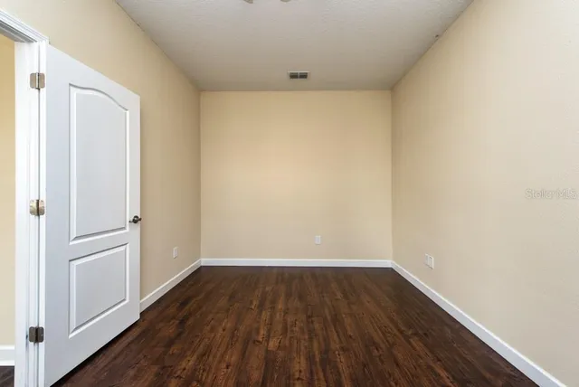 a view of empty room with wooden floor and window
