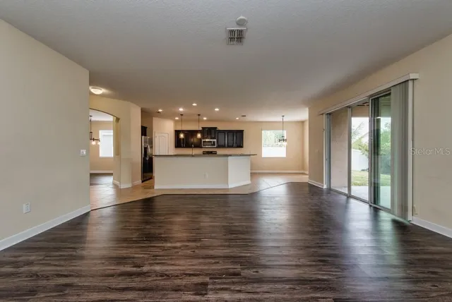 a view of a big room with wooden floor and a kitchen