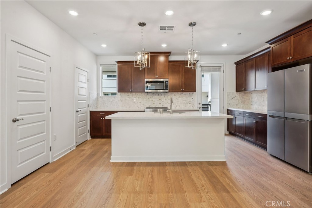a large kitchen with stainless steel appliances kitchen island a large counter top and a stove top oven