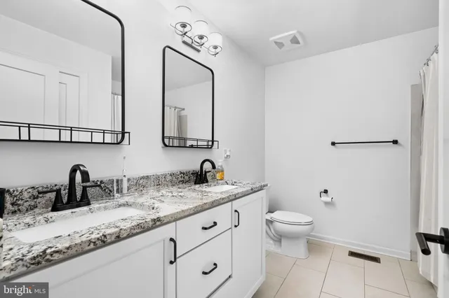 a bathroom with a double vanity sink toilet and mirror