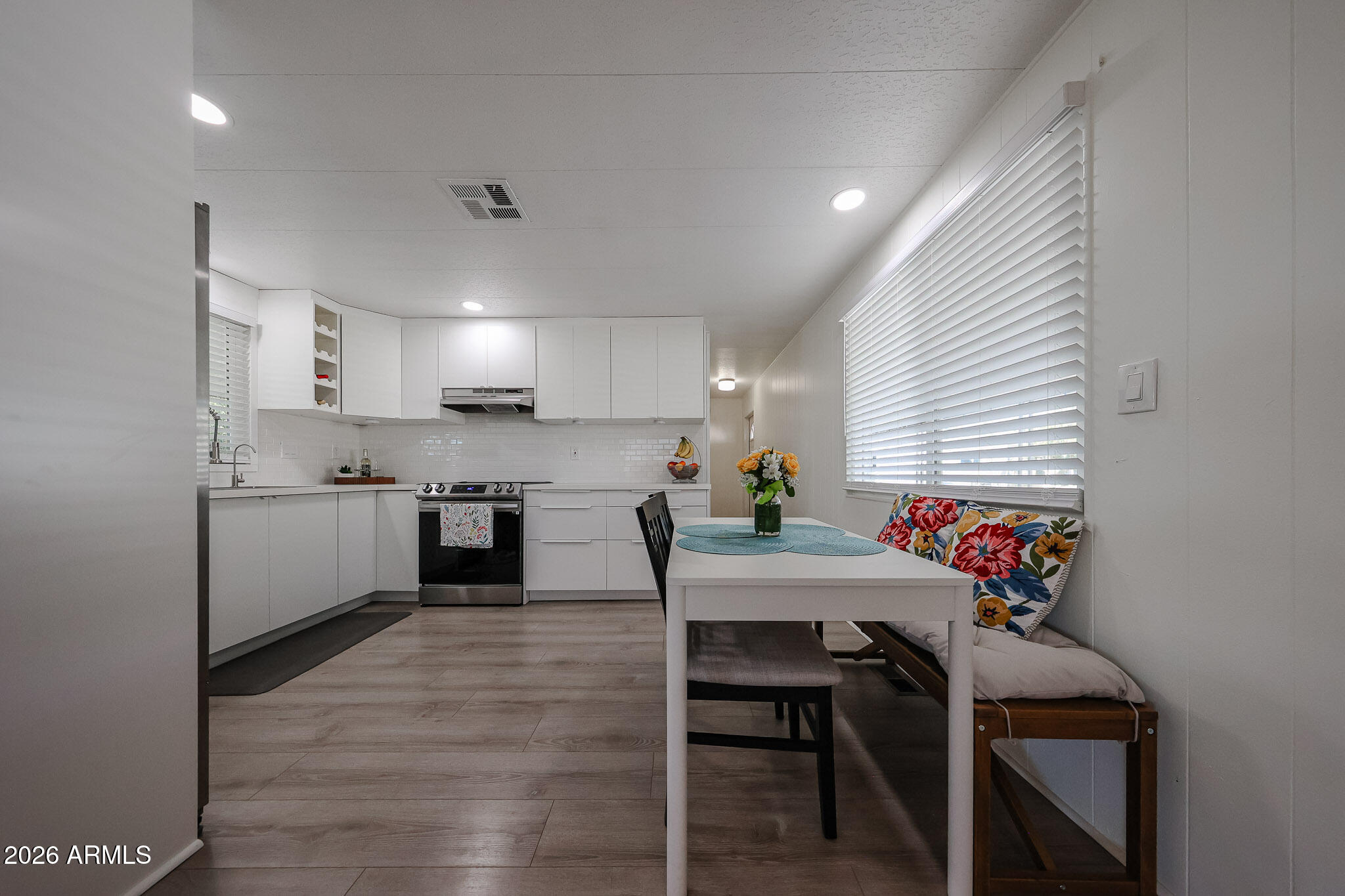 3104 East Broadway Road, Unit 216 Mesa, AZ 85204 - Photo 8 of 37 a kitchen with stainless steel appliances granite countertop sink wooden floor dining table and chairs