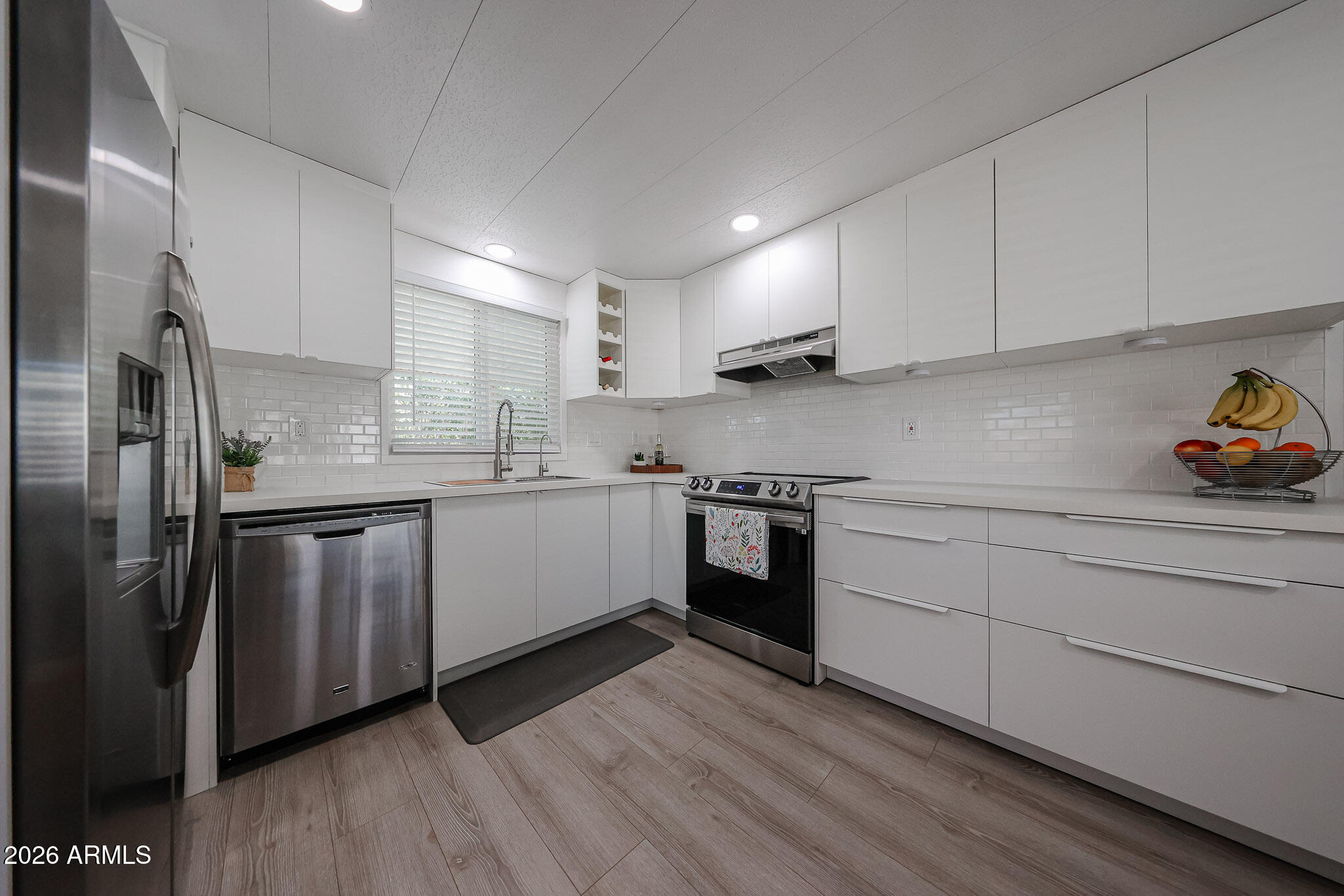 3104 East Broadway Road, Unit 216 Mesa, AZ 85204 - Photo 9 of 37 a kitchen with stainless steel appliances sink a refrigerator and white cabinets
