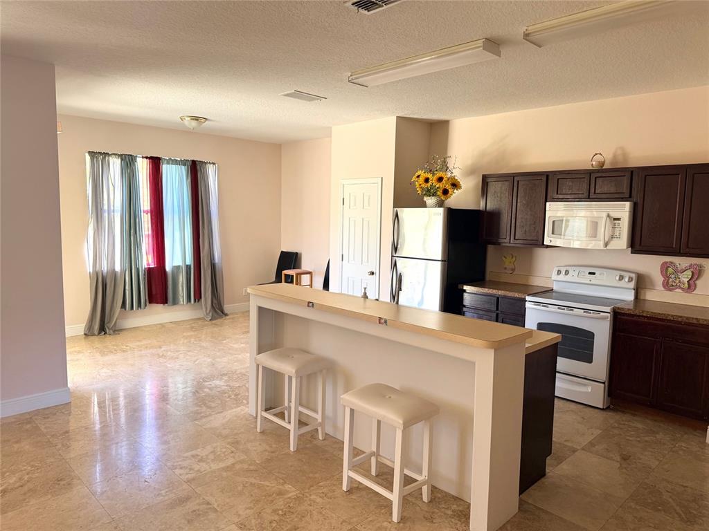 963 North Jacks Lake Road Clermont, FL 34711 - Photo 38 of 39 a kitchen with stainless steel appliances kitchen island granite countertop a stove top oven a sink dishwasher and a refrigerator with wooden floor
