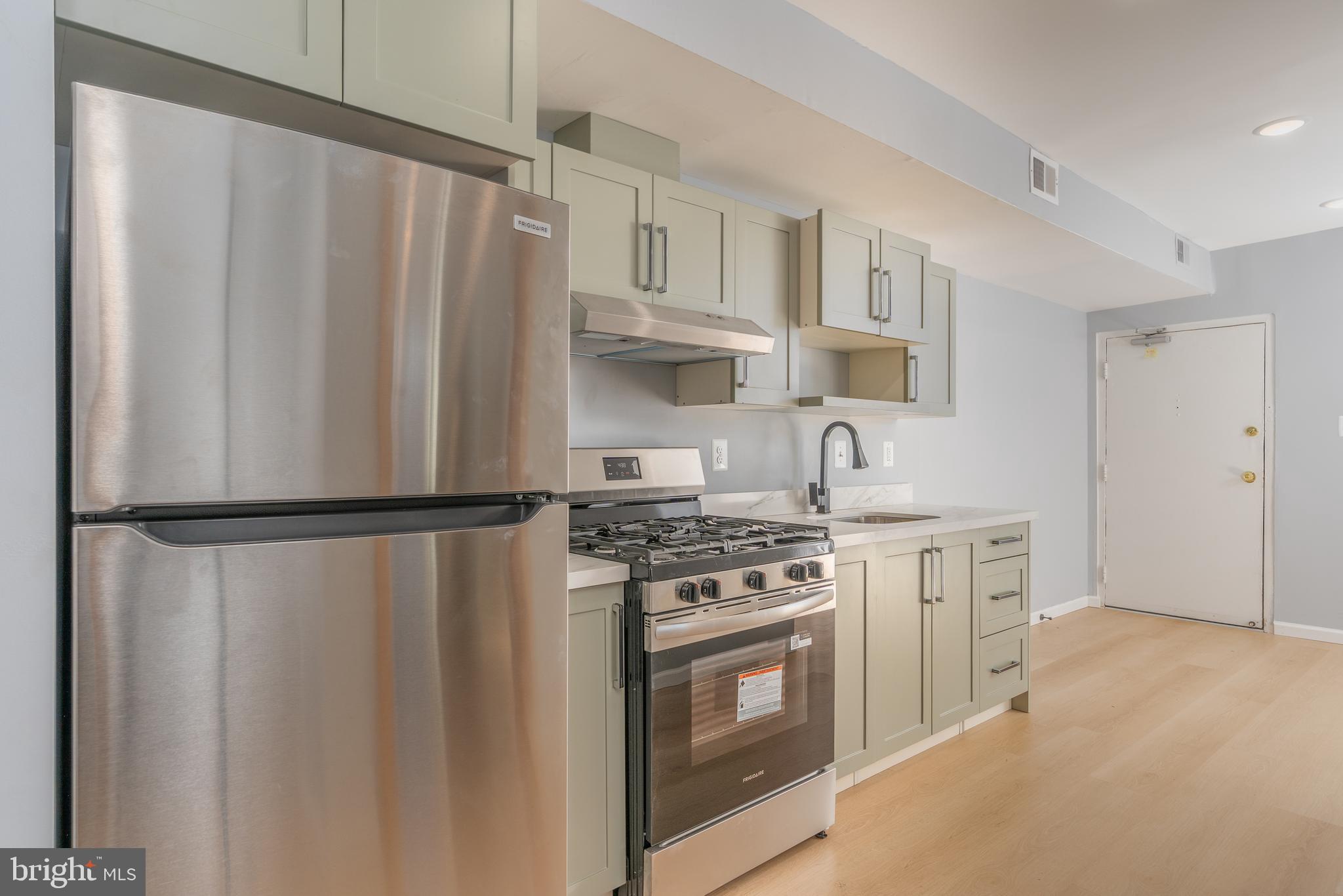 4936 Nash Street Northeast, Unit 9 Washington, DC 20019 - Photo 5 of 17 a kitchen with stainless steel appliances a refrigerator a stove and white cabinets