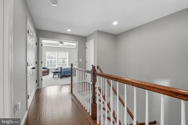 a view of a hallway with couches and dining table with wooden floor