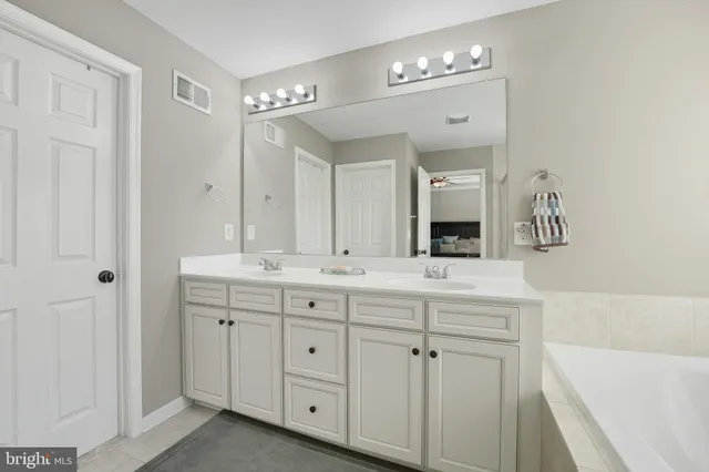 a bathroom with a double vanity sink mirror and bathtub