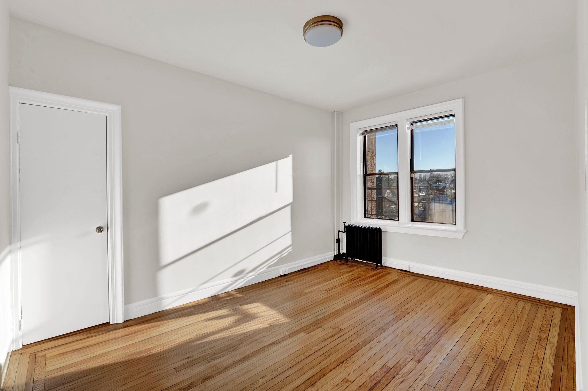 275 Harrison Avenue, Unit E5 Jersey City, NJ 07304 - Photo 11 of 17 an empty room with wooden floor and windows