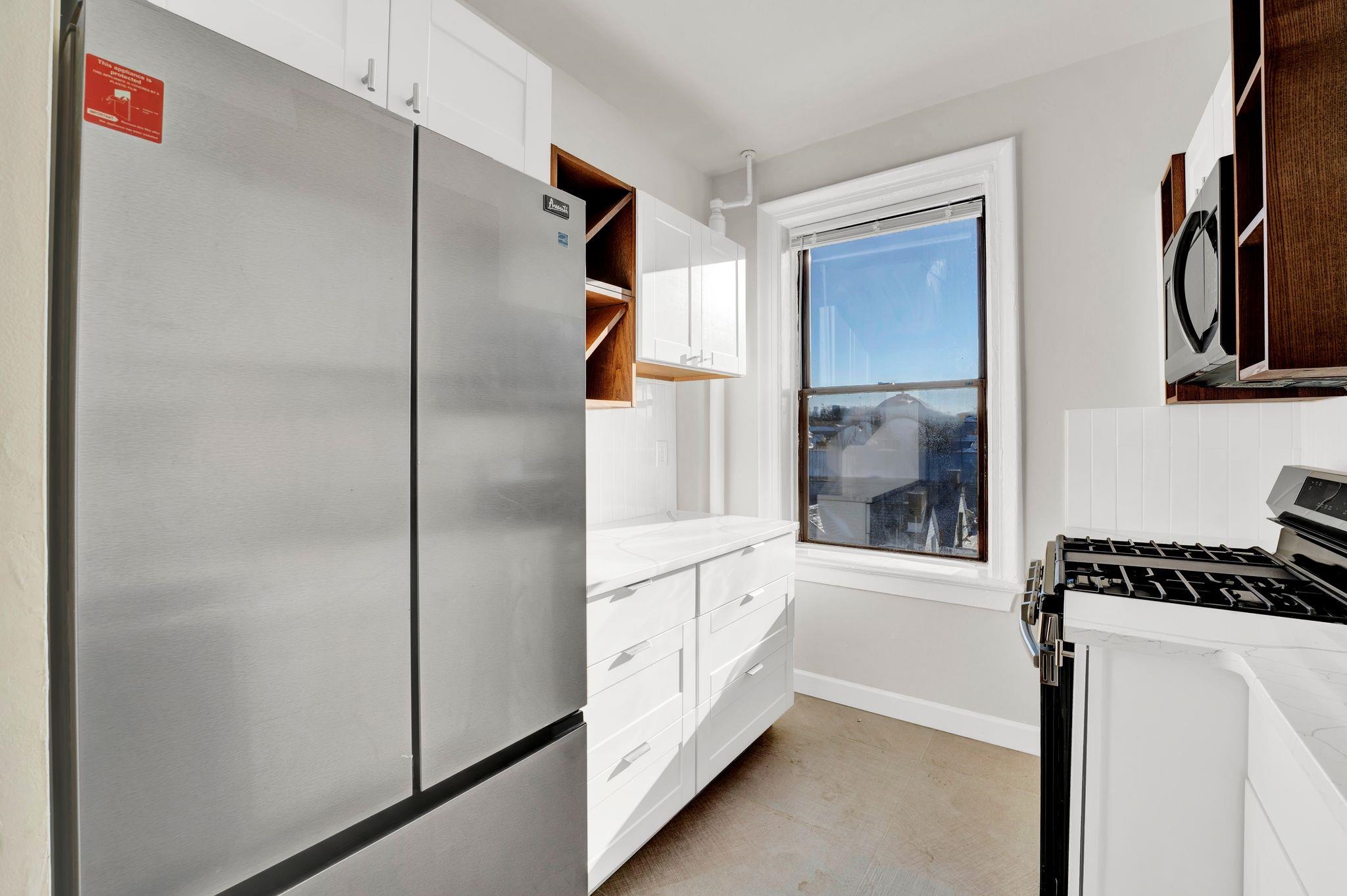 275 Harrison Avenue, Unit E5 Jersey City, NJ 07304 - Photo 3 of 17 a kitchen with white cabinets and black appliances