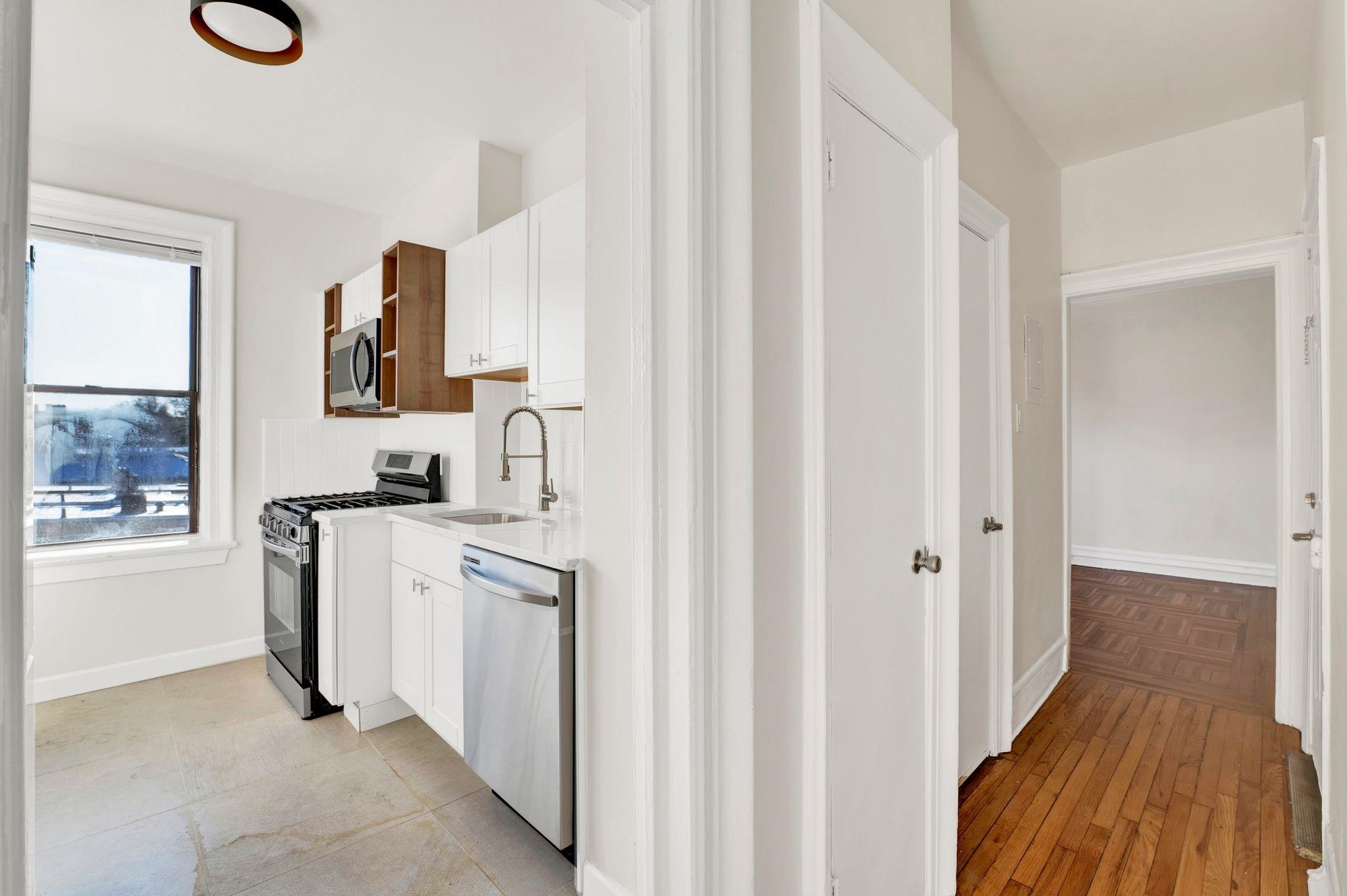 275 Harrison Avenue, Unit E5 Jersey City, NJ 07304 - Photo 4 of 17 a kitchen with white cabinets and white appliances