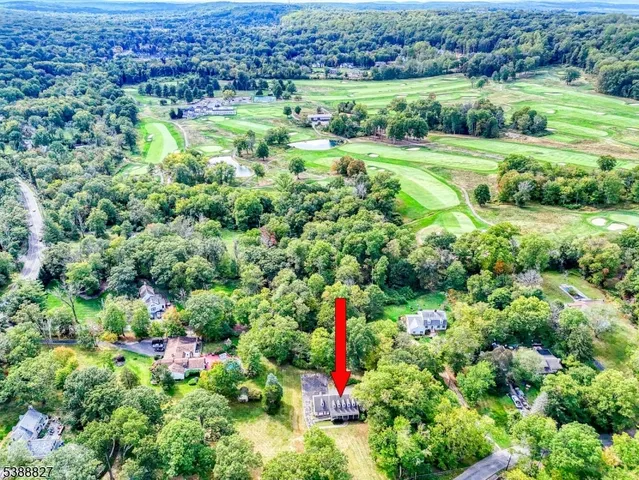 an aerial view of residential house with outdoor space and trees all around