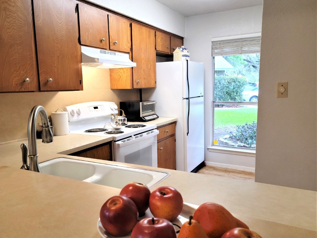 6904 Argonne Forest Cove, Unit A Austin, TX 78759 - Photo 6 of 25 a kitchen with stainless steel appliances granite countertop a sink a stove and a refrigerator