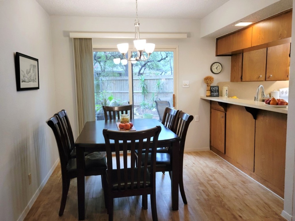 6904 Argonne Forest Cove, Unit A Austin, TX 78759 - Photo 9 of 25 a dining room with furniture a chandelier and wooden floor