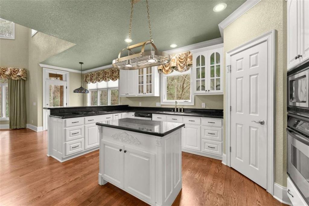 777 Oak Pointe Drive Cleveland, GA 30528 - Photo 21 of 63 a large kitchen with granite countertop a stove top oven a chimney cabinets and wooden floor