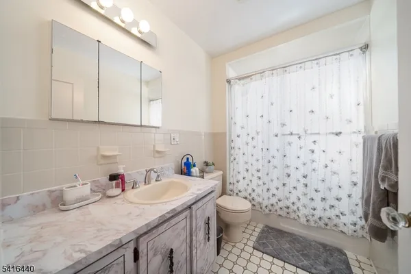 a bathroom with a granite countertop sink a toilet and a shower