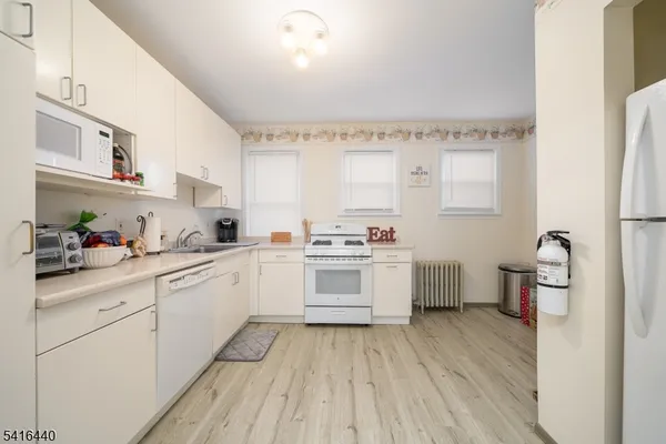 a kitchen with a white cabinets a sink dishwasher and a stove with wooden floor