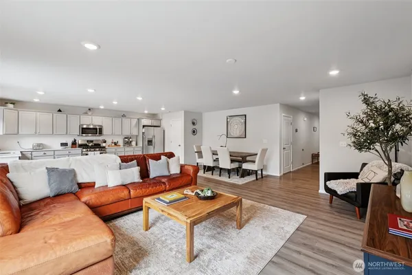 a living room with furniture kitchen view and a wooden floor