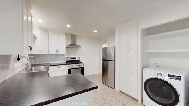 a kitchen with stainless steel appliances granite countertop a refrigerator a sink a stove and white cabinets