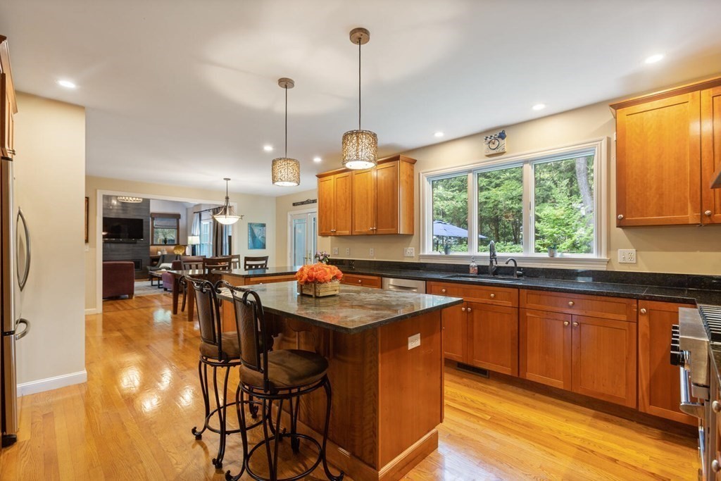 34 Woodcliffe Road Lexington, MA 02421 - Photo 11 of 34 a kitchen with stainless steel appliances granite countertop a stove top oven a dining table and chairs with wooden floor
