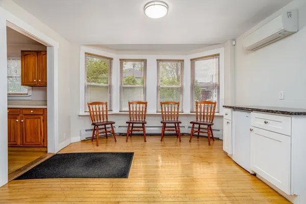 a living room with stainless steel appliances granite countertop a couch and a dining table with wooden floor