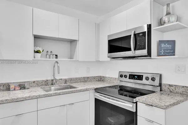 a kitchen with stainless steel appliances granite countertop a sink stove and microwave