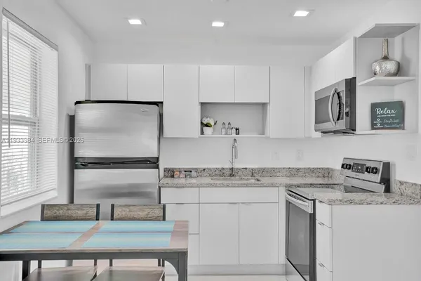 a kitchen with kitchen island granite countertop a sink cabinets and stainless steel appliances
