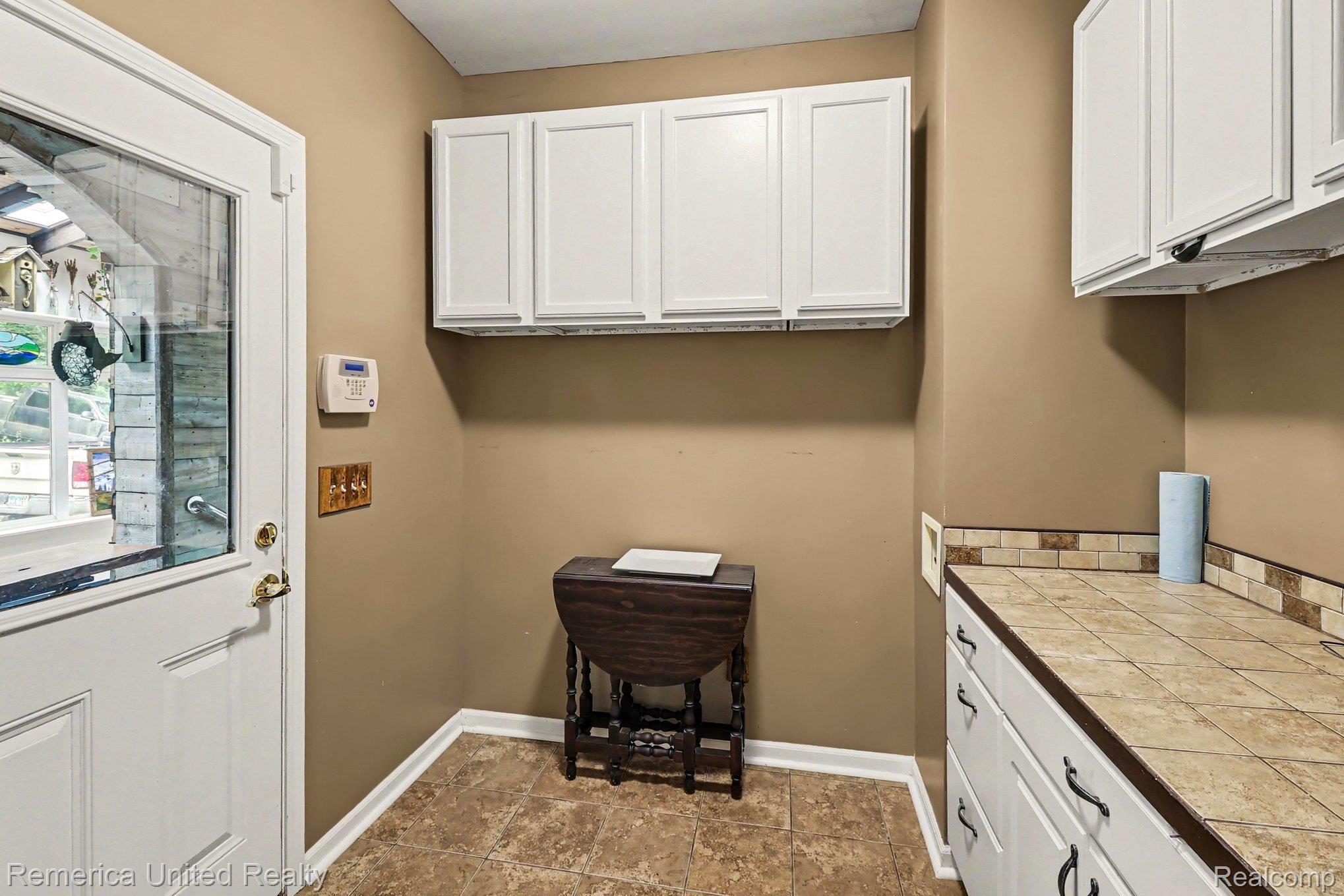 20962 Wasson Road Gregory, MI 48137 - Photo 26 of 39 Kitchen or utility space featuring white upper and lower cabinetry, tile flooring, and a tile countertop with a matching tile backsplash