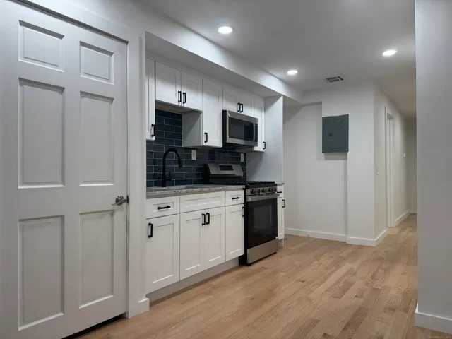 a large white kitchen with stainless steel appliances granite countertop a stove a sink and a refrigerator