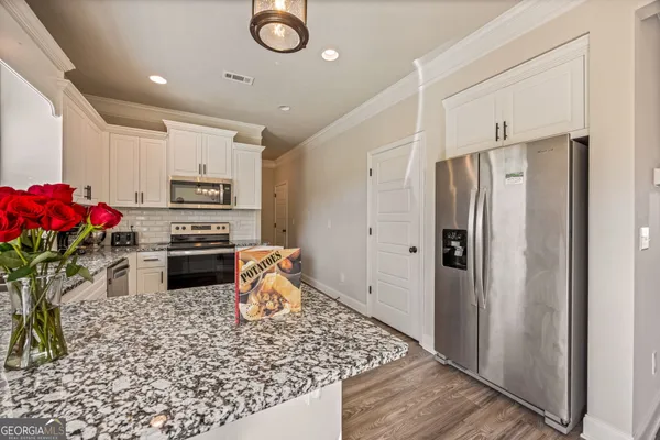 a kitchen with stainless steel appliances kitchen island granite countertop a table chairs stove and white cabinets