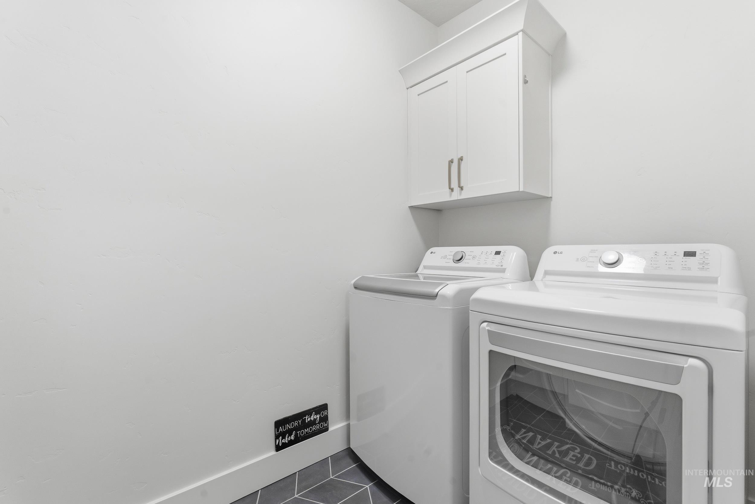 6347 South Utmost Lane Meridian, ID 83642 - Photo 28 of 37 Laundry area featuring a wall-mounted white cabinet with brushed nickel hardware, light gray walls, and geometric pattern flooring