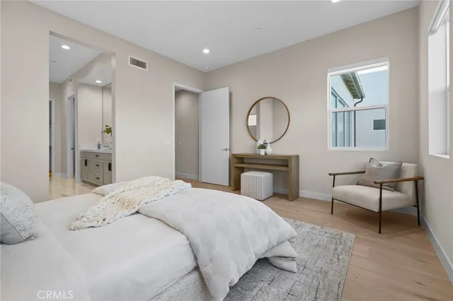 a bedroom with a bed a mirror and a potted plant