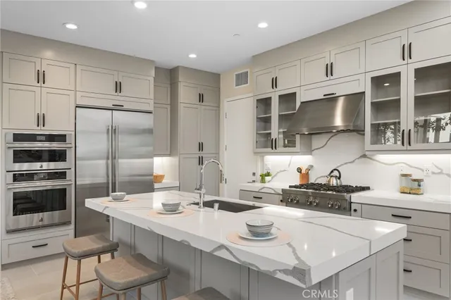 a kitchen with stainless steel appliances a sink a stove a refrigerator cabinets and dining table