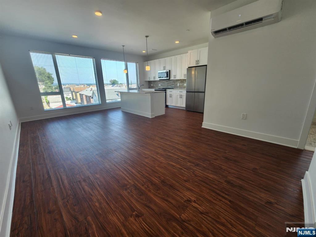 77 Ridge, Unit 306 North Arlington, NJ 07031 - Photo 4 of 23 an empty room with wooden floor and windows