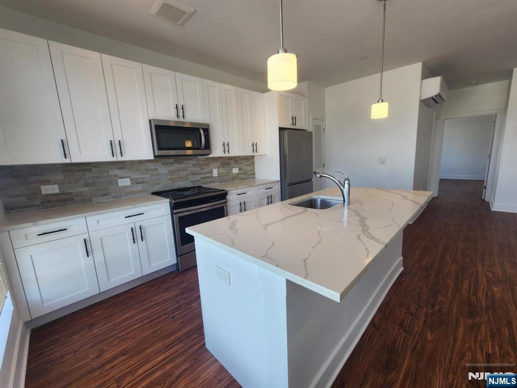 77 Ridge, Unit 306 North Arlington, NJ 07031 - Photo 6 of 23 a kitchen with stainless steel appliances granite countertop a sink a microwave counter space and wooden floor