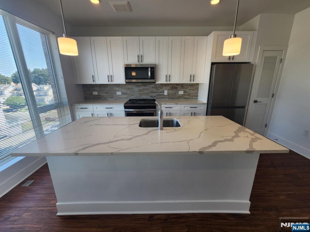 77 Ridge, Unit 306 North Arlington, NJ 07031 - Photo 8 of 23 a kitchen with kitchen island a sink a stove a microwave a refrigerator and cabinets