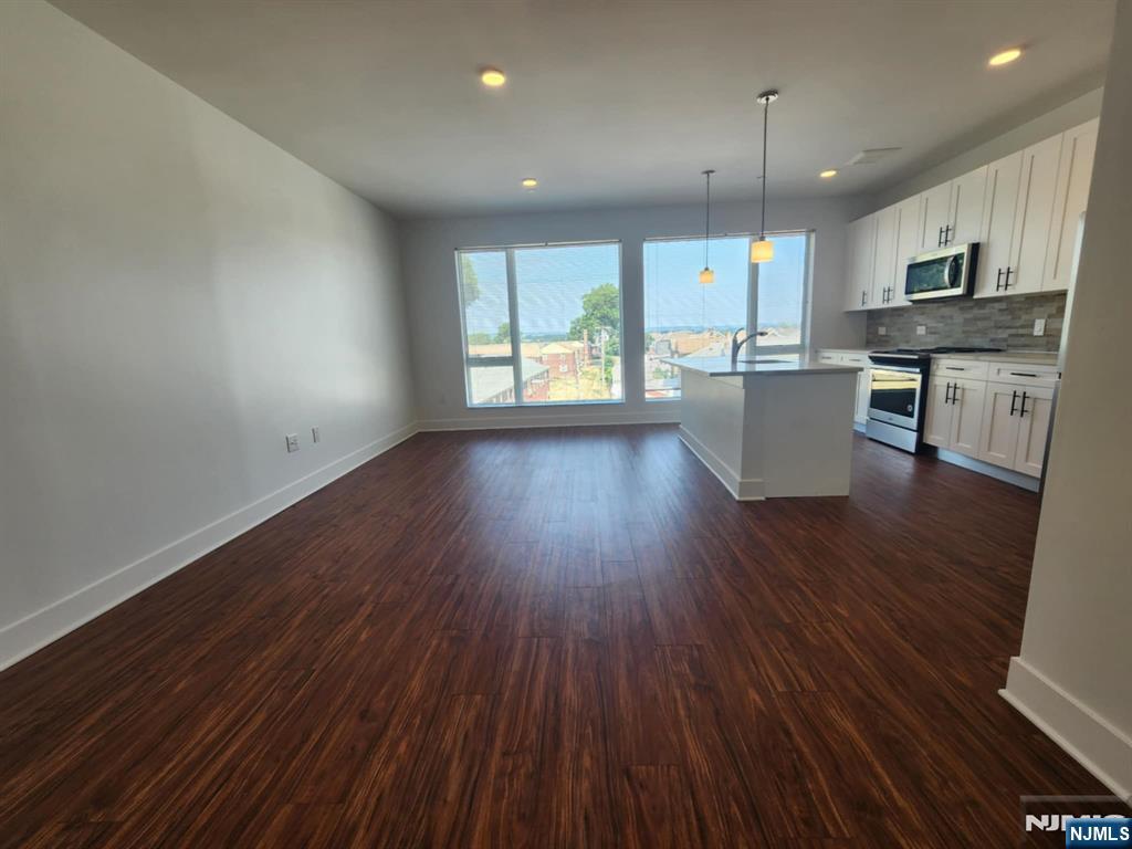 77 Ridge, Unit 306 North Arlington, NJ 07031 - Photo 10 of 23 an open kitchen with wooden floors and white cabinets